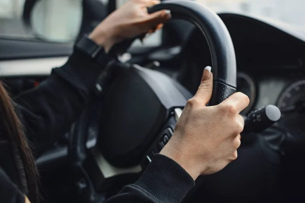 Women\'s hands on the wheel of a car while driving