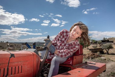 Çiftçi kadın çiftliğinde traktör manevrası yapıyor.