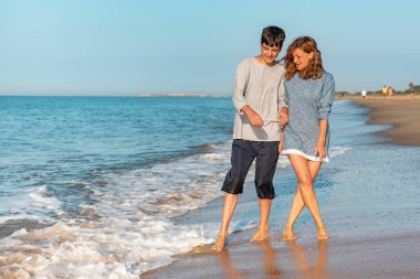 Anne ve genç sahildeki dalgalarla eğleniyorlar.