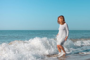 Sahilde dalgalarla oynayan bir kadın