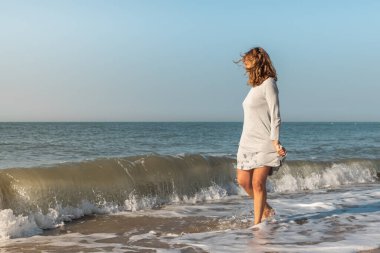 Sahilde dalgalarla oynayan bir kadın