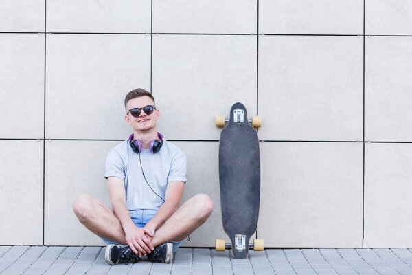 Man with Longboard Before Bricks Wall