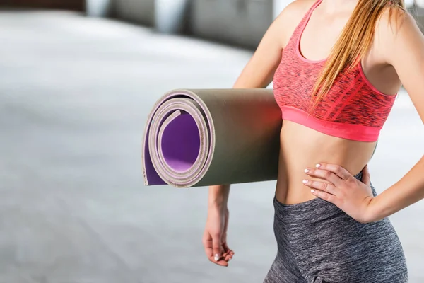 Sport flicka håller Sport matta på gymmet — Stockfoto