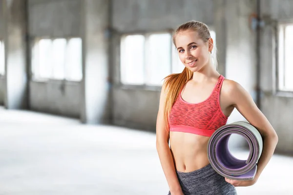 Linda mujer joven en desgaste deportivo celebración Yoga Mat — Foto de Stock