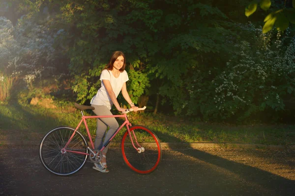 Девушка, гуляющая с велосипедом на закате — стоковое фото