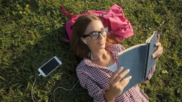 Kız çimlerin üzerine kitap okur — Stok video