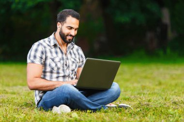 Açık havada dizüstü bilgisayarda çalışan erkeğin sakallı