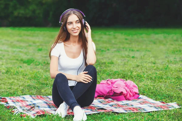 Jovem mulher em fones de ouvido no parque de verão — Fotografia de Stock