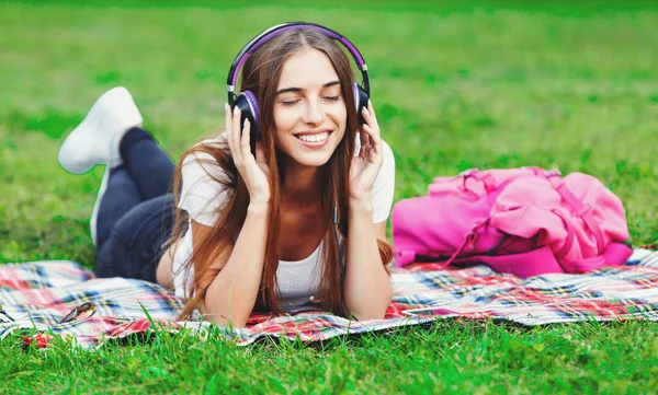 Jovem mulher em fones de ouvido no parque de verão — Fotografia de Stock