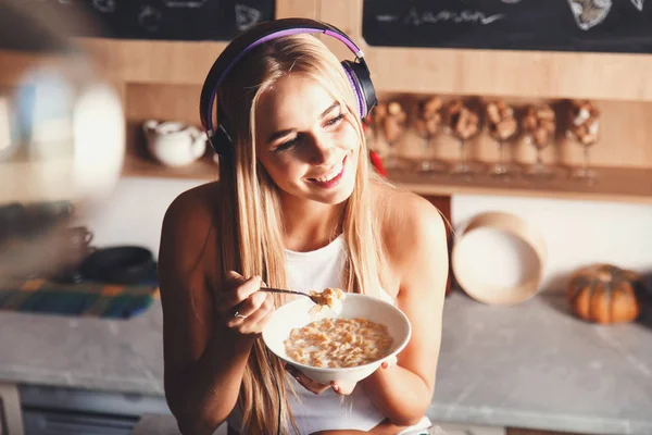 Блондинка слушает музыку и ест завтрак — стоковое фото