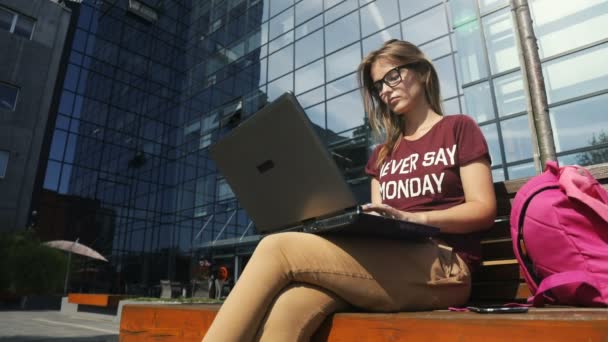 Mujer utiliza el ordenador portátil al aire libre — Vídeo de stock