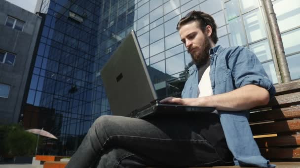 Homem usa laptop ao ar livre — Vídeo de Stock