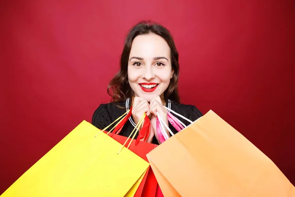 Mujer atractiva posando en el estudio con bolsas de compras de papel —  Fotos de Stock