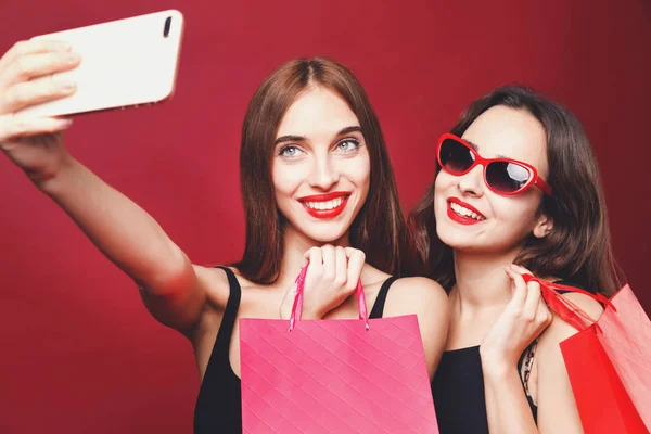 Két barátnő, gazdaság, könyv bevásárló táskák, és így Selfie — Stock Fotó