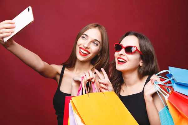 Zwei Freundinnen halten Papiereinkaufstüten in der Hand und machen Selfie — Stockfoto