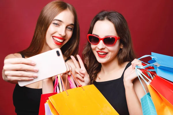 Zwei Freundinnen halten Papiereinkaufstüten in der Hand und machen Selfie — Stockfoto