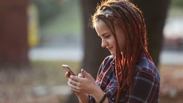 Adolescente utiliza el teléfono en el parque — Vídeos de Stock