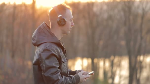 Homem ouve música perto do lago — Vídeo de Stock