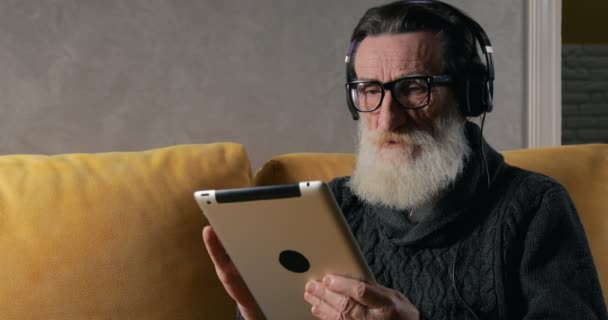 Starszy człowiek słucha wiadomości na Tablet — Wideo stockowe