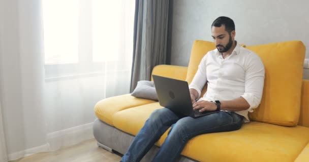 Hombre utiliza el ordenador portátil en la sala de estar — Vídeos de Stock