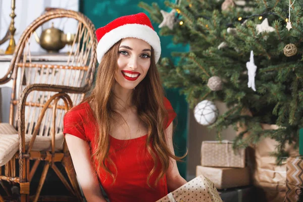 Emocionada mujer de Navidad con sombrero de Santa sentado cerca del abeto de Año Nuevo — Foto de Stock