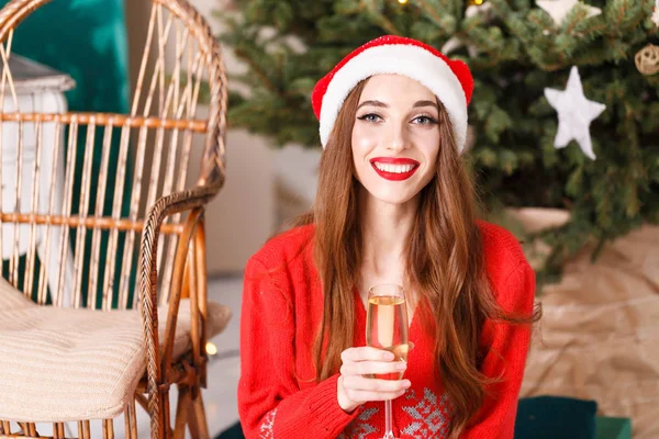 Atractiva mujer de Navidad con sombrero de Santa sentado cerca del abeto — Foto de Stock