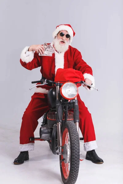 バイクの上に座って、お金を保持しているサングラスのサンタ クロース — ストック写真
