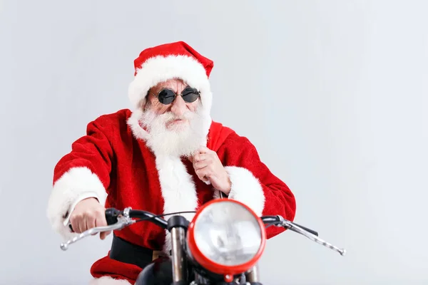 Santa Claus v sluneční brýle na koni A motocyklu a drží tašku — Stock fotografie