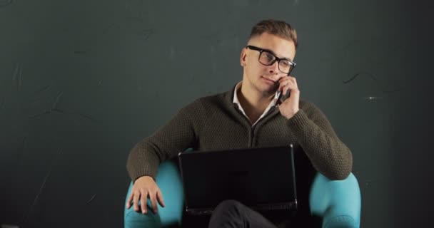 Hombre con el ordenador portátil habla por teléfono — Vídeos de Stock