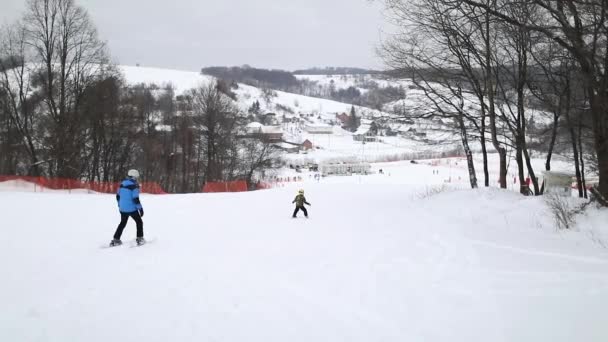 Dziecko i trener jazdy na nartach w dół wzgórza — Wideo stockowe