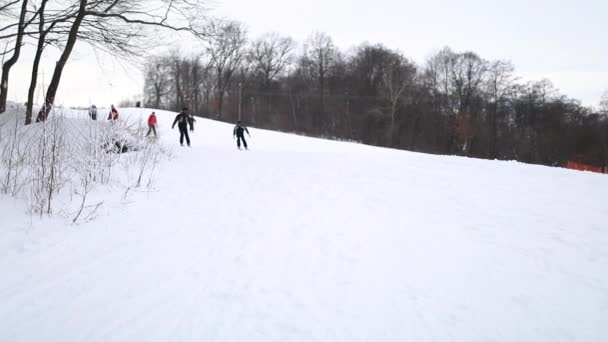 Lidé lyžování dolů z kopce, snowboardisty — Stock video