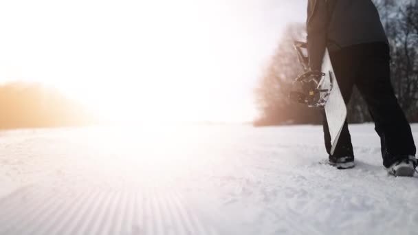 Retour Prise de vue d'un snowboardeur marchant tenant du snowboard — Video