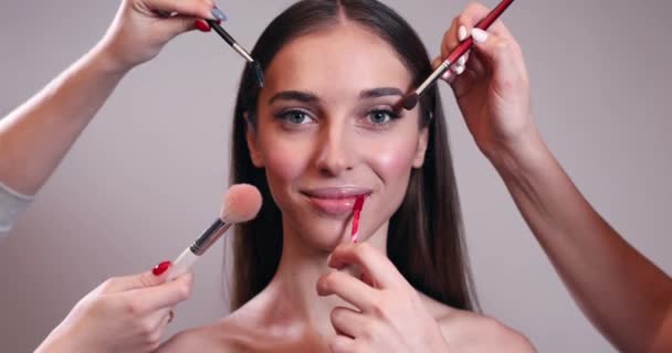 Múltiples manos haciendo maquillaje de mujer joven — Vídeo de stock