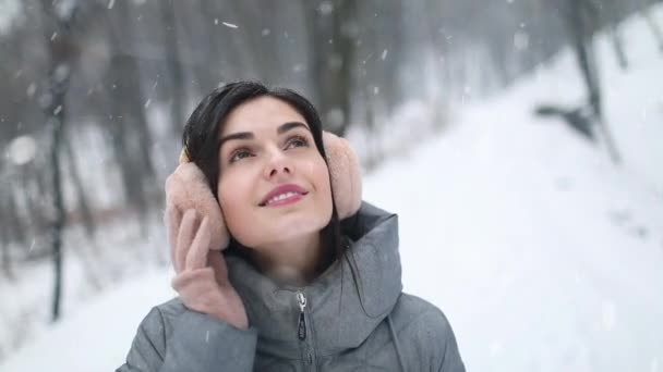 Девушка смотрит на небо во время снегопада в лесу — стоковое видео