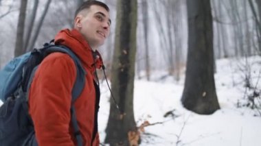 Sırt çantalı bir adam ormanda yürüyor.