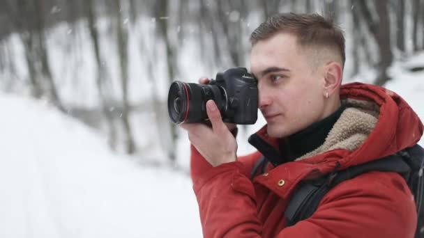 Человек фотографируется с камерой в лесу — стоковое видео