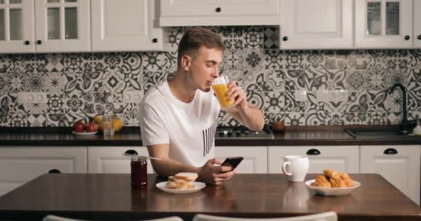 Jovem homem bebendo suco e usando Smartphone — Vídeo de Stock