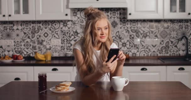 부엌에서 스마트폰을 사용 하 여 아름 다운 여자 — 비디오