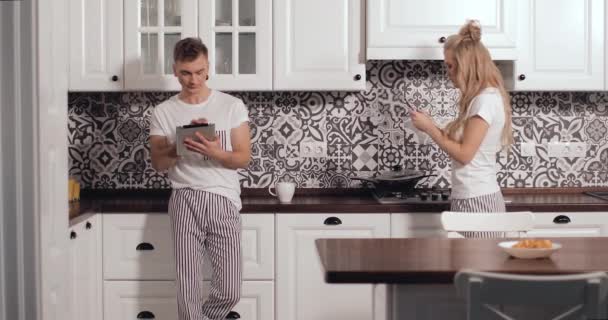 Couple debout utilisant des gadgets dans la cuisine — Video