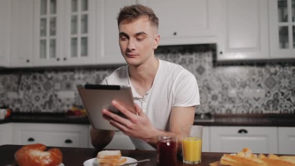 Zamyślony człowiek za pomocą tabletu w kuchni — Wideo stockowe