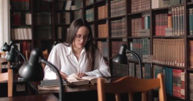 kız kütüphanede kitap okuyor.