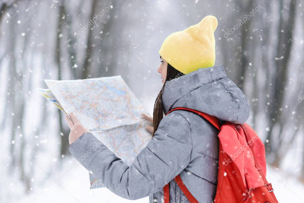 Girl Walking with the Map in the Winter Snowy Forest