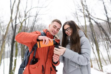 Genç bir çift kış ormanında yürüyor.