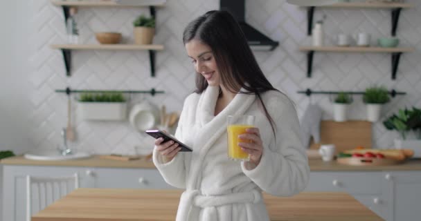 Ragazza allegra Scorrere sul telefono e bere succo di frutta — Video Stock