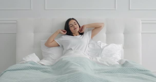 Молодая девушка растягивает тело в постели — стоковое видео