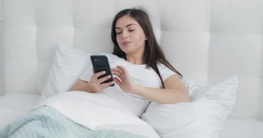 Güzel kız yatakta Smartphone kullanarak