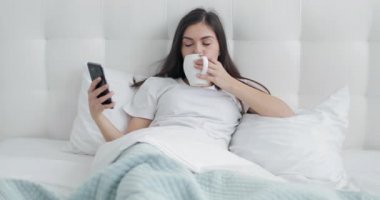 Kız telefonu kullanarak ve yatakta kahve