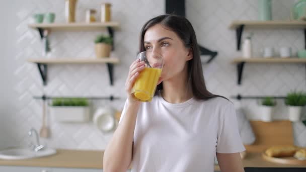 Девушка пьет апельсиновый сок на кухне — стоковое видео