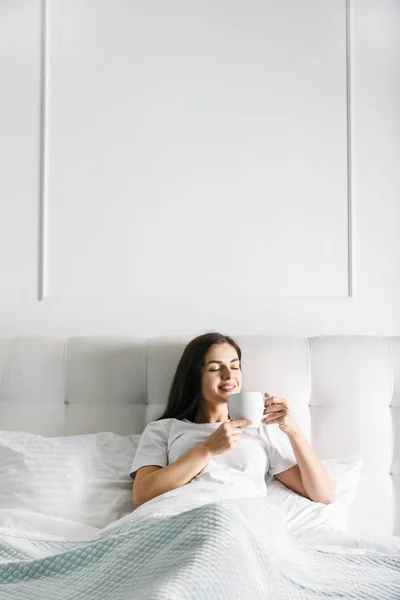 Mujer tomando café en la cama —  Fotos de Stock