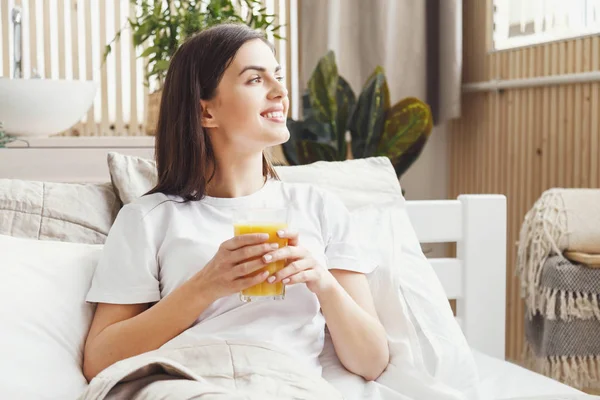 Mujer bebiendo jugo en la cama — Foto de Stock